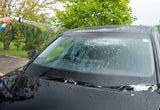 Washing a black car with a high-pressure water sprayer on the windshield