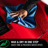 Hand using a blue microfiber towel to dry a red car with Turtle Wax Hybrid Solution Ceramic Wet Wax.