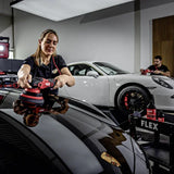 Professional detailer using FLEX polisher on luxury car hood in garage