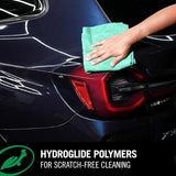 Hand using a green microfiber towel to clean a dark car with Turtle Wax Ceramic 3in1 Detailer.