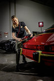 Professional detailing a red Porsche with a polishing machine in a garage