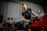 Professional detailer using FLEX polisher on red car in garage with car care products