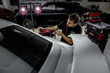 Man using FLEX polisher on white car in detailing garage with FLEX lights and tools