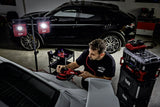 Man using FLEX car polisher on white vehicle in garage with FLEX lighting and storage, detailing a black SUV nearby