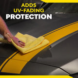 Hand applying UV-fading protection to black car with yellow stripes using microfiber towel