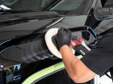 Professional car detailing with polishing machine on glossy black vehicle
