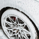Foamy car wheel detailing with red brake calipers and sleek alloy rims