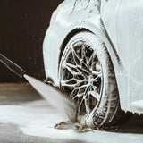 Pressure washing foamy car wheel during detailing, showcasing deep clean for car care enthusiasts