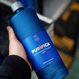 A person holding a bottle of Labocosmetica PURÌFICA Acid Decontaminant Shampoo.