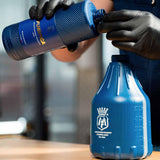 Person in black gloves pouring Labocosmetica PURIFICA shampoo into a blue container.