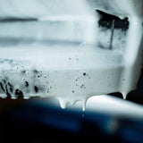 Thick white Labocosmetica PURÌFICA shampoo foam clinging to a car surface during detailing.