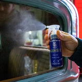 A person spraying Labocosmetica AQUAVÈLOX Glass Nano Sealant onto a car window.