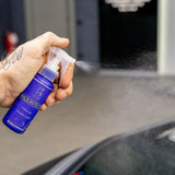Hand spraying Labocosmetica AQUAVÈLOX Glass Nano Sealant onto a car window.