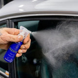 Hand spraying Labocosmetica AQUAVÈLOX Glass Nano Sealant onto a car window.