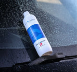 Bottle of Bilt Hamber Phat-Neut multi-mode rinseless wash on a wet car windshield