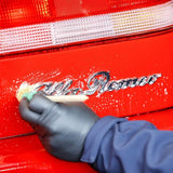 Detailing a car emblem with Labocosmetica ÈNERGO Mineral Stain Remover using a small brush.