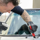 Detailer using Labocosmetica mineral stain remover and a brush on a car windshield
