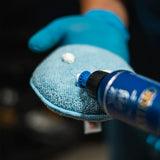 Labocosmetica Vitreo Glass Polish being applied to a blue microfiber cloth by a gloved hand.