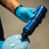 A hand in blue gloves applying Labocosmetica Vitreo Glass Polish to a blue microfiber cloth.
