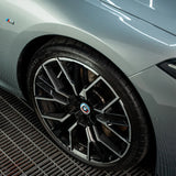 Close-up of a glossy black and silver alloy wheel on a grey car treated with Labocosmetica.