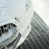 A car covered in thick white snow foam during a Labocosmetica PRÌMUS 2.0 prewash process.