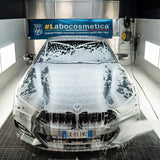 BMW car covered in snow foam during a Labocosmetica prewash treatment in a professional studio