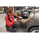 Detailer using a car polisher tool on a luxury car door in a garage setting